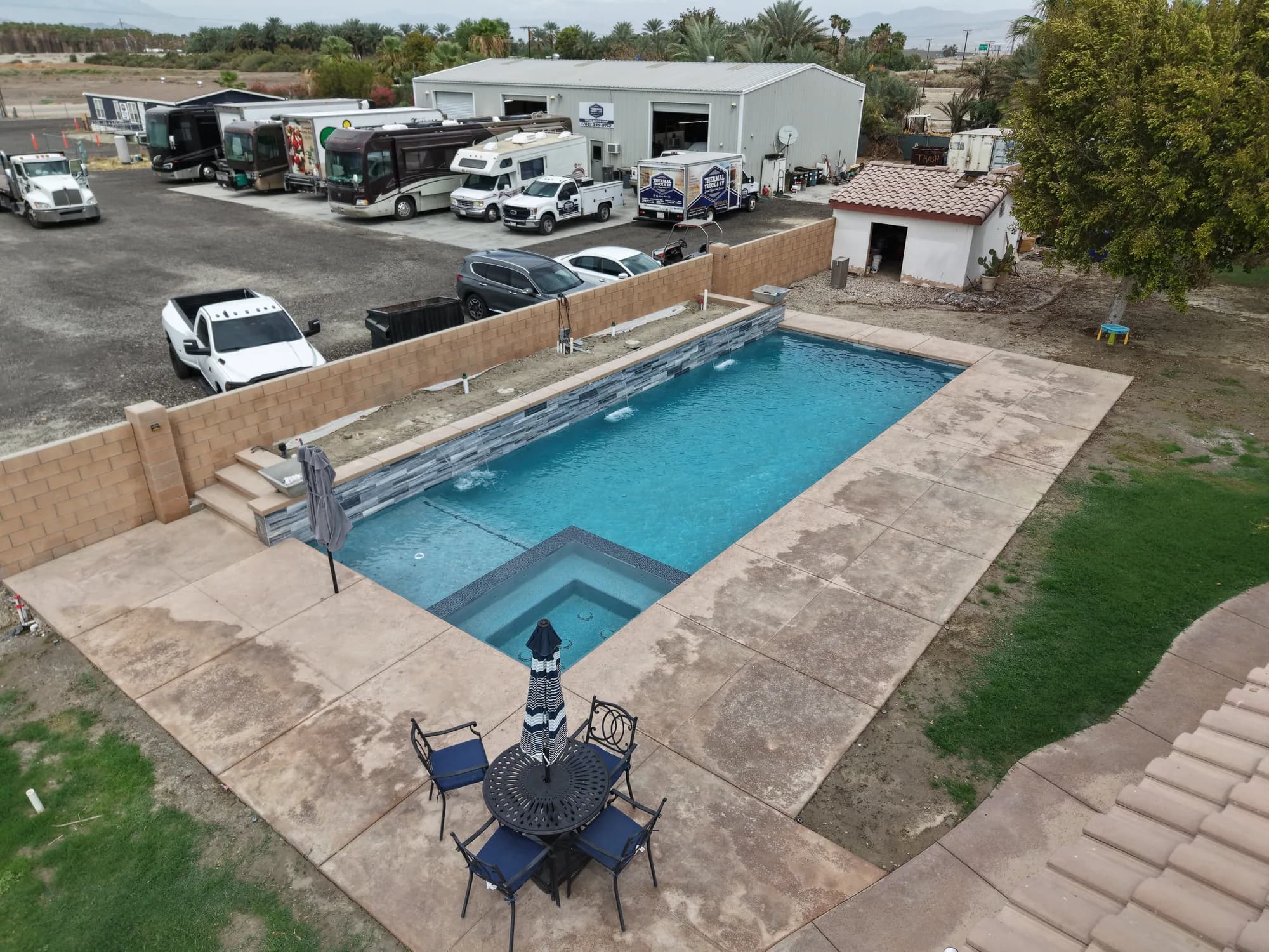 Aerial view of a finished modern pool, spa, and outdoor living area
