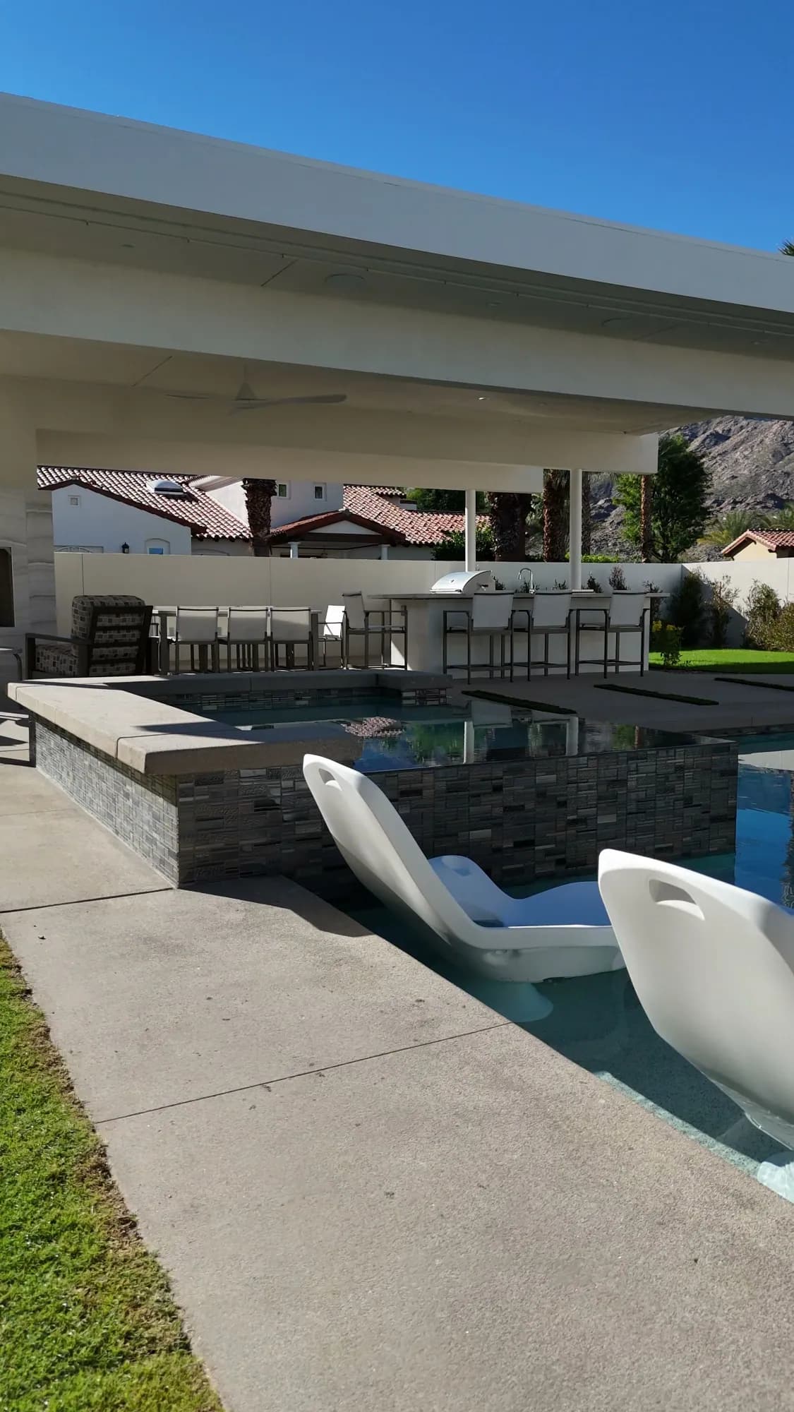 Outdoor kitchen and lounge area connected to a custom pool