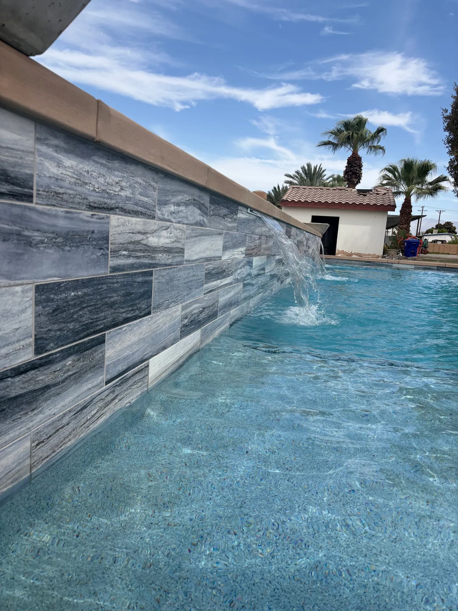 Stone waterline tile and light pool finish at the 56 AVE project by JB Pools