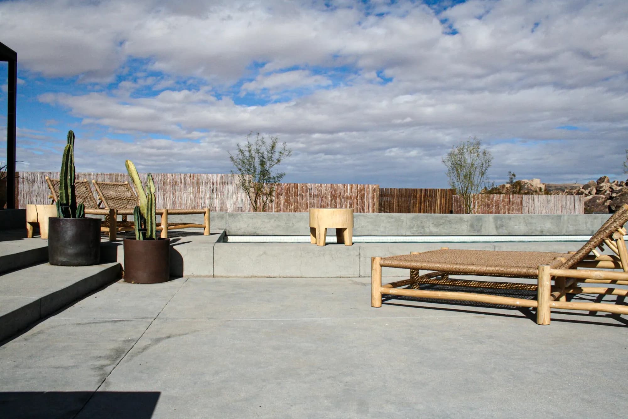 Poolside lounge chairs, desert planting, and a coordinated concrete terrace in Joshua Tree